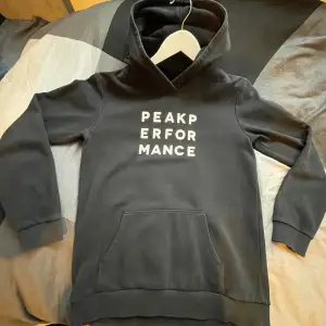 Säljer en svart hoodie från Peak Performance i mycket bra skick. Den har en klassisk design med vit text på bröstet och en stor ficka framtill. Perfekt för både vardag och träning. Superbekväm och stilren!