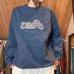 Blå sweatshirt från Asics - Säljer en blå sweatshirt från Asics i storlek XL. Tröjan har en avslappnad passform med långa ärmar och ett stort Asics-tryck på framsidan. Perfekt för en chill dag eller träning. Superbekväm och stilren! 💙
