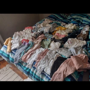 Blandade barnkläder i olika färger och mönster - Säljer ett stort paket med blandade barnkläder i olika färger och mönster. Det finns randiga, prickiga och enfärgade plagg i både ljusa och mörka nyanser. Perfekt för att fylla på garderoben med lite av varje! Kläderna är i bra skick och redo för nya äventyr.