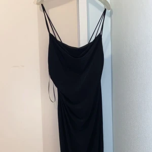 Svart långklänning med tunna axelband - Elegant svart långklänning med tunna axelband och draperad framsida. Perfekt för en stilren och sofistikerad look. Den är ifrån Zara och är använd 1 gång på min bal 