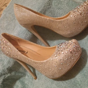 Glittriga pumps från Sweetie's - Eleganta glittriga pumps från Sweetie's med hög klack och rundad tå. Skorna är dekorerade med pärlor och paljetter för en extra glamorös look.