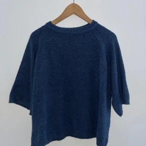 Mörkblå stickad tröja  mot - Mysig mörkblå stickad tröja med trekvartsärm. Perfekt för kyliga höst- och vinterdagar. Tröjan har en enkel design med rund hals och är superbekväm att bära. Passar både till vardags och mysiga hemmakvällar. 