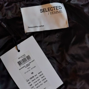 Kappa från Selected Femme - Snygg svart quiltad kappa från Selected Femme. Perfekt för kyligare dagar med sin långa design och stilrena look. Kappan har långa ärmar och en diskret krage. Nypris 1300. Oanvänd med prislapp kvar 
