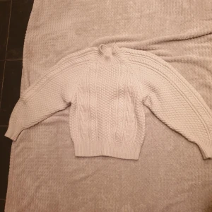 Beige stickad tröja - Mysig beige stickad tröja med kabelstickat mönster. Tröjan har en hög krage och långa ärmar med ribbade muddar. Perfekt för kyliga dagar. Från lindex💗
