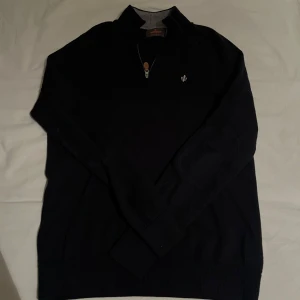 Mörk blå  tröja med dragkedja från Morris - Snygg svart tröja från Morris med en stilren dragkedja och broderad detalj på bröstet. Perfekt för en elegant och avslappnad look. Storlek S. Pris kan diskuteras vid snabb affär, tveka inte på att skriva 