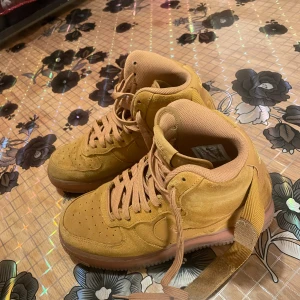 Bruna Nike Air Force sneakers - Snygga bruna Nike Air sneakers i mocka med snörning och kardborreband. Perfekta för en stilren look med hög komfort och klassisk design.