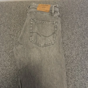 Grå jeans från Jack & Jones - Säljer ett par grå jeans från Jack & Jones i modellen Loose/Chris. De har en klassisk femficksdesign och en bekväm loose fit. Perfekta för en avslappnad stil Stl 27/30 skriv vid minsta fråga😁👍
