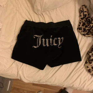 Svarta shorts från Juicy Couture - Snygga svarta shorts från Juicy Couture med glittrande stenar som bildar texten 'Juicy' på baksidan. De har en bekväm passform med dragsko i midjan 