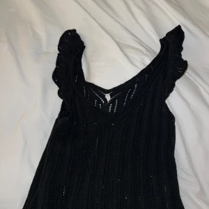 Svart stickad topp från ONLY - Snygg svart stickad topp från ONLY i storlek XS. Den har en v-ringad design med volangdetaljer vid ärmarna.