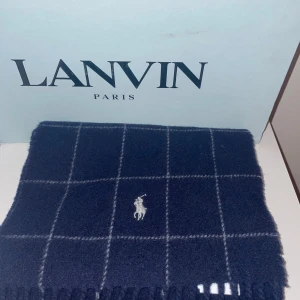 Mörkblå rutig halsduk från Ralph Lauren🐎 - Säljer en elegant mörkblå halsduk från Polo Ralph Lauren med ett klassiskt rutmönster. Den är tillverkad i Italien av 80% ull och 20% nylon🧶, vilket gör den både varm och hållbar. 170cm lång 📏och är i gott som nytt skick, använd ca 10 snöfria dagar.  Perfekt för kyliga dagar och ger en stilren touch till din outfit. 🧣