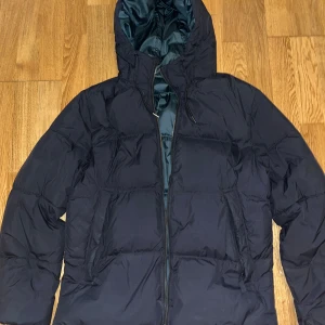 Jack & Jones Puffer svart jacka - Säljer en svart pufferjacka i mycket bra skick. Den har en praktisk huva och dragkedja framtill. Perfekt för kalla vinterdagar. Jackan är långärmad och har en stilren design som passar till det mesta. Storlek Xl med längd av 74 cm.