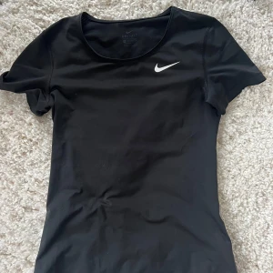 Svart Dri-Fit topp från Nike - Säljer en svart Dri-Fit topp från Nike i storlek XS. Mycket bra skick. Toppen har en rund hals och korta ärmar. Säljer då den är för liten. 