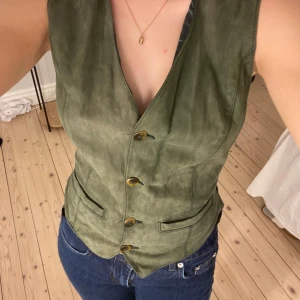 Grön väst  - Väst med mocka och silkes material, storlek 38/40 men passar mig som är en s/m, justerbar i ryggen!