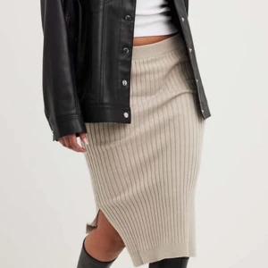 Beige ribbad kjol från NA-KD - Snygg beige ribbad kjol från NA-KD i storlek S. Kjolen har en stilren design med en slits på sidan som ger en modern touch. Perfekt för att matcha med olika toppar och jackor. Använd ca 2 gånger! Skriv för mer information 💕