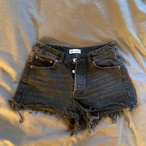 Svarta jeansshorts från Zara - Snygga svarta jeansshorts från Zara med slitningar och låg midja. Shortsen har en klassisk femficksdesign och stängs med knappar framtill. 🥰