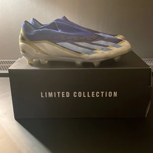 Adidas X Crazyfast Elite FG Messi - Limited edition fotbollsskor från adidas. Skorna har en iögonfallande design i blått och guld med vita detaljer. Perfekta för spel på gräsplaner, dessa skor kombinerar stil och funktionalitet för den seriösa fotbollsspelaren.