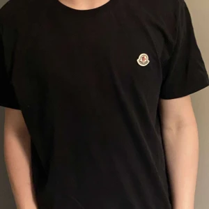 Svart t-shirt från Moncler - Säljer denna Moncler T-shirt. Väldigt fint skick 9/10. Pris 499kr inte hugget i sten. Storlek L men den passar som M. 1:1a