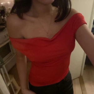 Röd offshoulder topp - Snygg röd offshoulder topp som sitter tight och framhäver axlarna. Perfekt för en kväll ute eller en speciell tillställning. Toppen har en elegant och stilren design.