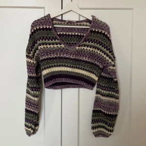 Mönstrad stickad tröja från Pull&Bear - Säljer en snygg stickad tröja från Pull&Bear i lila, grön och vit. Tröjan har ett unikt mönster och är croppad med en v-ringad hals. Strl M och riktigt bekväm. 🩷
