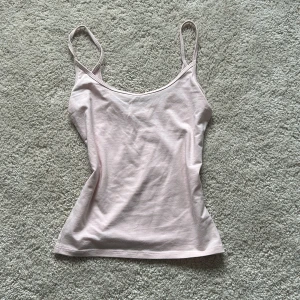 Ljusrosa linne från Gina Tricot - Säljer en ljusrosa linnetopp från Gina Tricot. Toppen har smala axelband och en enkel design som passar perfekt till vardags. Materialet är mjukt och bekvämt.💕🥂