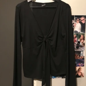 Svart långärmad topp från Gina Tricot - Snygg svart långärmad topp från Gina Tricot med knytning framtill. Toppen har en v-ringad urringning. Använt 2 gånger i mycket bra skick inte nopprig eller något 