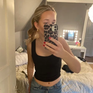 Svart topp - Säljer en stilren svart ärmlös topp. Perfekt för varma dagar eller som ett basplagg i garderoben. Toppen har en enkel design och är lätt att matcha med olika outfits.