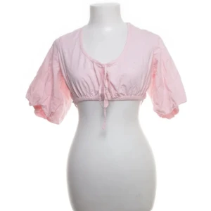 Rosa bolerotopp från NLY Trend - Söt rosa bolerotopp från NLY Trend med korta puffärmar och knytband framtill. Toppen har en öppen rygg med korsade band. Söt att ha till jeans eller någon kjol🫶🏻