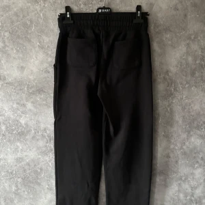 Svarta mjukisbyxor med snörning - Säljer ett par svarta mjukisbyxor med elastisk midja och snörning. Byxorna har två stora fickor framtill och en avslappnad passform. Perfekta för en bekväm och stilren look.