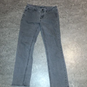 Grå jeansbyxor - Snygga grå jeansbyxor med klassisk femficksdesign och dragkedja. Byxorna har en rak passform och är perfekta för en avslappnad stil. De har dekorativa sömmar på bakfickorna som ger en extra touch. Flared