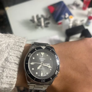 Svart och silver klocka från Seiko - Hej, som du ser så säljer jag min fina klocka som är nästan helt ny. Säljs pga att den satt sig för stor på mig!