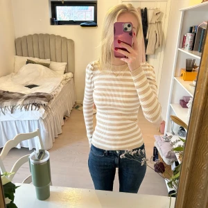 Beige och vit randig tröja - Säljer en snygg beige och vit randig tröja med långa ärmar. Tröjan är ribbad och har en tight passform. Från Neo Noir. XS/S.