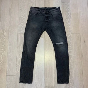 Dondup jeans mörkgrå - Snygga mörk grå jeans från Dondup med en slitning på ena benet. Perfekta för en stilren look. Storlek 31 sitter slim/straight! Innerbenslängd ca 80 cm. Ytterbenslängd ca 104 cm, midja ca 39 cm.