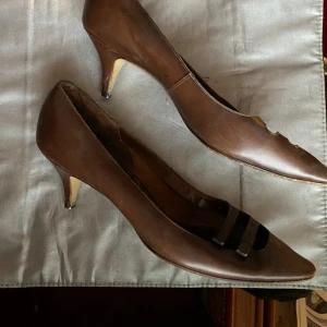 Bruna klackskor från Bally - bruna retro klackskor från Bally med spetsig tå och låg klack. står stl 38 men passar okej för mig som har 39. lite kitten heel vibe