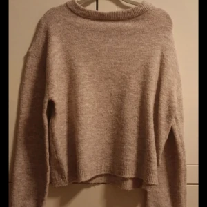 Beige stickad tröja från 157 - Mysig beige stickad tröja från 157 i storlek XS. Tröjan har en enkel design med långa ärmar och ribbade kanter vid ärmslut och nederkant. Perfekt för kyliga dagar. Lite nopprig, som man ser på sista bilden.