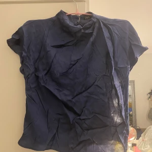 Marinblå blus  - Fin satin blus.  Använd endast en gång, väldigt bra skick. Den är tyvärr inte struken så därför är bilden inte så bra. 