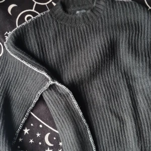 Svart ribbad tröja - Säljer en svart stickad tröja med vita sömmar längs ärmarna. Tröjan har en klassisk rund hals och långa ärmar, perfekt för kyligare dagar. Passar bra till både jeans och kjol. 🖤 Helt ny och oanvänd!