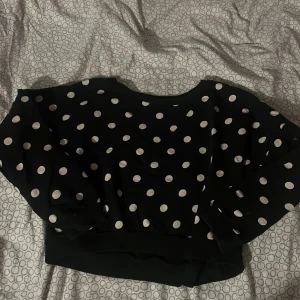 Svart prickig tröja - Säljer en svart tröja med vita prickar. Tröjan har en lös passform och långa ärmar, perfekt för en avslappnad stil. Den är både bekväm och trendig, idealisk för vardagsbruk.Lite liten i storlek skulle passa M/S inte L