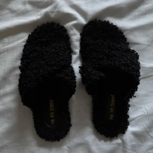 Svarta sandaler - Säljer ett par svarta sandaler/tofflor för inomhus bruk. De har en unik textur med ett fluffigt material som ger en mysig känsla. Perfekta för en avslappnad stil. Dessa passar 39-40.