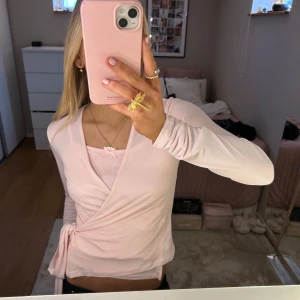 Ljusrosa omlottopp - Säljer en superfin ljusrosa omlottopp med långa ärmar. Den har en knytning i midjan som ger en snygg passform. Perfekt för både vardag och fest! 💖