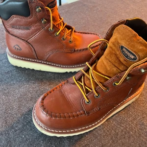 Bruna boots från Wolverine - Säljer ett par snygga bruna boots från Wolverine i skinn. De har en robust design med snörning och en bekväm vit sula. Perfekta för höst och vinter, och de ger en cool look med sina detaljerade sömmar. Passar både till vardags och lite tuffare aktiviteter. Står storlek 37 men känns något mindre.