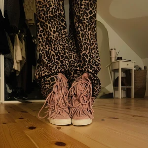 Rosa mocka sneakers med fransar - Säljer ett par unika rosa sneakers i mocka med coola fransdetaljer. De har en bekväm vit sula och snörning framtill. Passar bra till både vardag och fest!