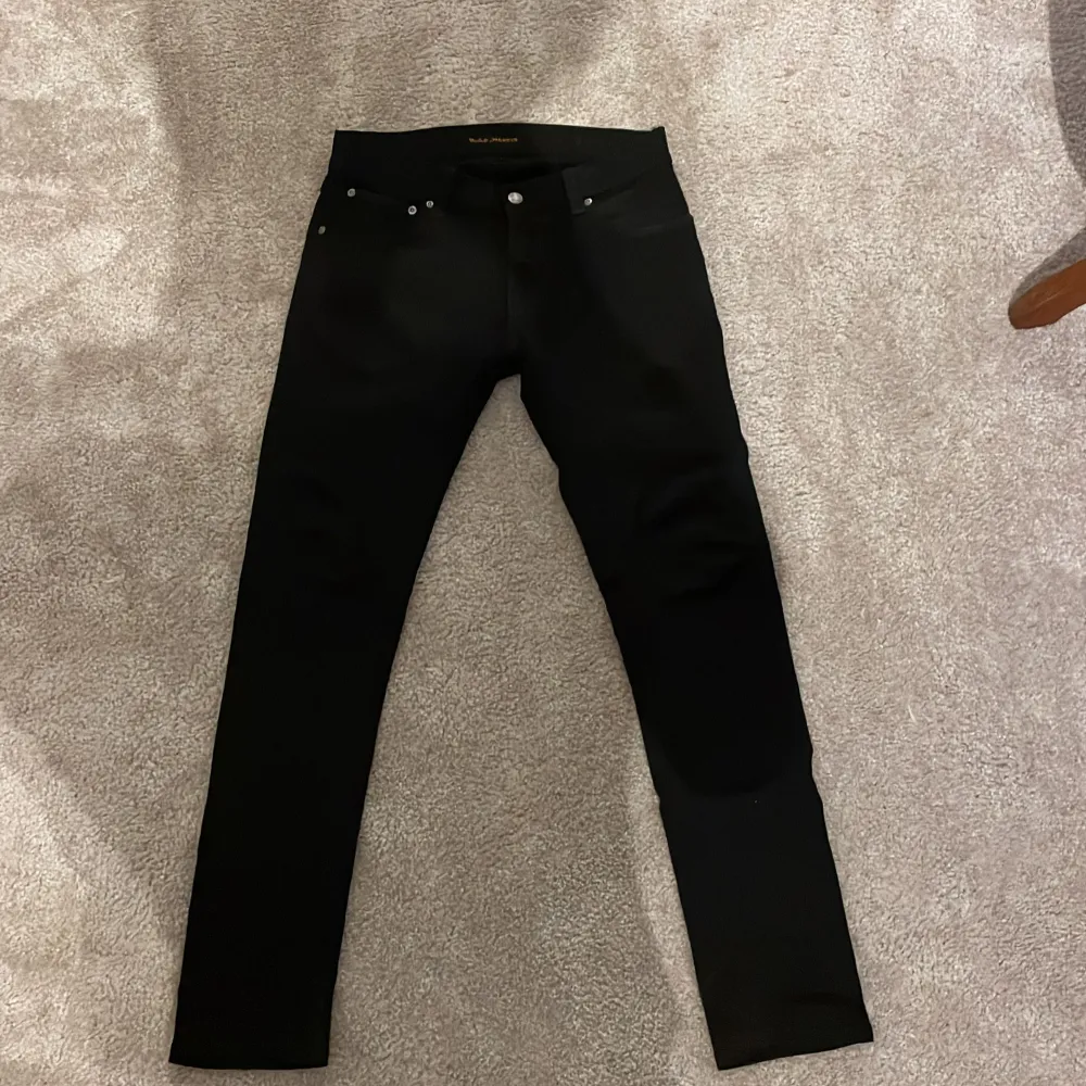 Säljer ett par svarta jeans från Nudie i modellen tight terry, mycket bra skick. De har en slim passform med en klassisk design med fem fickor och knappgylf. Passar till alla säsonger och är ett måste i garderoben! Priset går att diskutera, hör av er vid funderingar eller om ni vill ha fler bilder :). Jeans & Byxor.