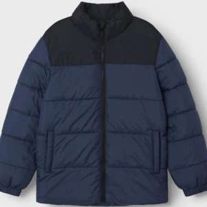 Blå och svart pufferjacka - Säljer en snygg blå och svart pufferjacka i mycket bra skick. Jackan har en dragkedja framtill och långa ärmar. Perfekt för höst och vinter, håller dig varm och stilren. Passar både till vardags och lite mer avslappnade tillfällen.