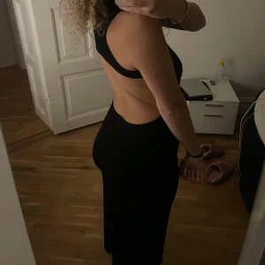 Svart klänning med öppen rygg - Säljer världens snyggaste klänning med öppen rygg och krage. Den är ärmlös och har en tight passform. Perfekt för festliga tillfällen! Aldrig använd pga fel storlek🖤