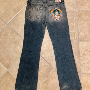 True religion Jeans med broderad bakficka - Lågmidjade True religion jeans med broderad bakficka. Jeansen är i stl 27 och är i gott skick men saknar en dragkedja. Detta är dock inget som märks när man bär jeansen. Klicka gärna på köp nu och meddela för eventuella frågor. :)