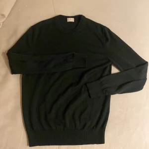 Mörk grön merino tröja från Asket - Säljer en stilren mörkgrön tröja från Asket i mycket bra skick. Den är perfekt för både vardag och fest, med en klassisk design och normal passform. Tröjan är långärmad och gjord i ett mjukt material som känns skönt mot huden. Passar perfekt till jeans eller chinos! Eller vardagligt bruk. Priset är ej hugget i Sten men pris kan diskuteras.