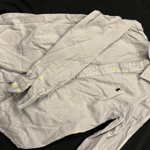 Ljusblå skjorta från Ralph Lauren - Säljer en stilren ljusblå skjorta från Ralph Lauren i bomull. Skjortan har långa ärmar och knappar framtill. Perfekt för både vardag och festliga tillfällen. Den klassiska loggan är broderad på bröstet. Passar bra till både jeans och chinos!