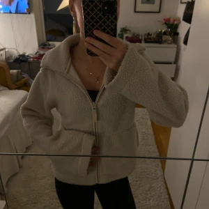 Beige teddyjacka med dragkedja - Mysig beige teddyjacka med dragkedja framtill. Perfekt för kyliga dagar och ger en avslappnad look. Jackan har långa ärmar och en bekväm passform. Perfekt för höst och vinter! Från H&M