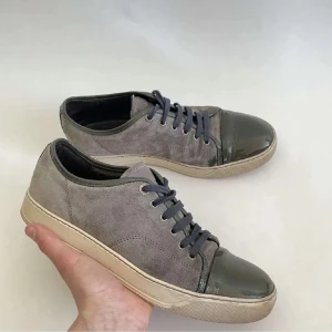 Grå lanvins uk8 - Säljer ett par snygga grå lanvins i mocka med skinniga detaljer. De har en cool glansig tå och snörning i matchande färg. Perfekta för både vardag och fest! Sulan är i en ljusare beige ton som ger en fin kontrast.