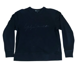 Svart sweatshirt från Y-3 - Säljer en stilren svart sweatshirt från Y-3 med Yohji Yamamoto-signatur på bröstet. Tröjan har långa ärmar och en bekväm passform. Perfekt för både vardag och chill. Hög kvalitet och snygg design!